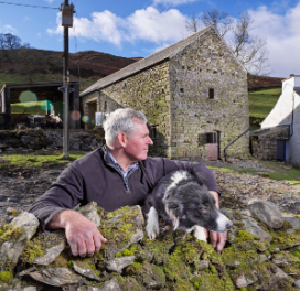 Farmer and sheepdog outside a restored barn