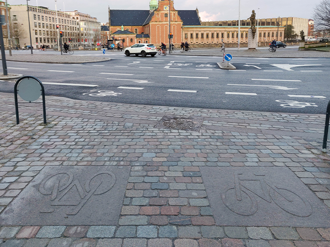 Cobbled street surface with a bicycle symbol laid in stone.