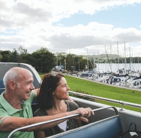 Couple aboard an open top but looking out ofver a lake and boats on a beautiful spring day 