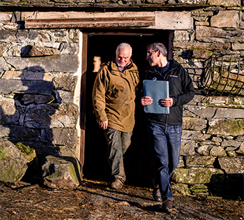 2 people stood in a doorway to a stone building
