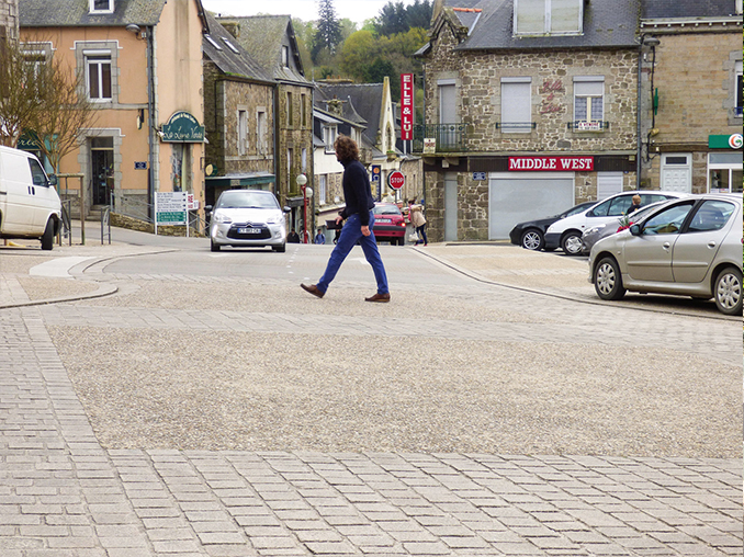 Cobbled area across a road in a village in France.