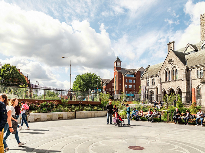 People sat on public outside seating in a city pedestrian area.