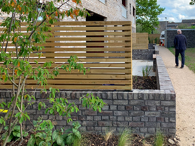 A slatted wooden fence on top of a low brick wall.