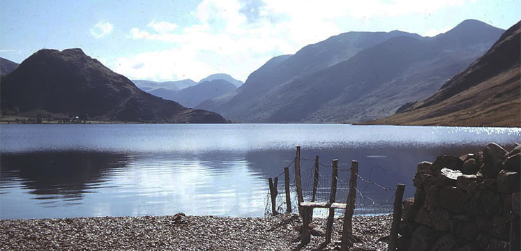 A pebble lakeshore with high fells on the far shore