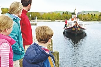 family looking out over the water with boat voming towards them in the distance