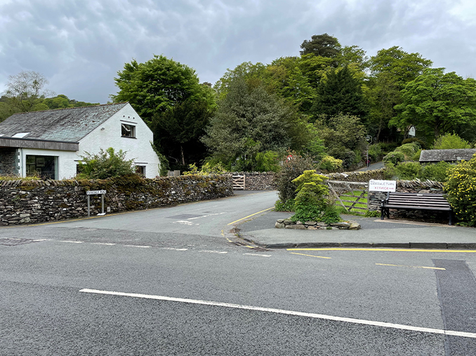 Road junction with signs set into stone wall.