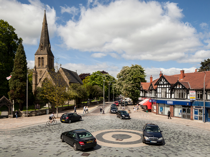 Cars and cyclists at a stone laid roundabout