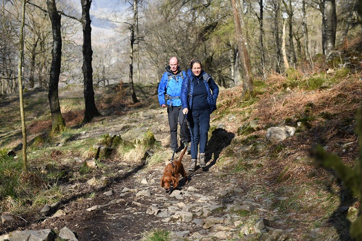 Two people walking with a dog on a lead.