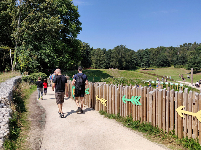 Colourful arrows along a wooden fence next to a path.