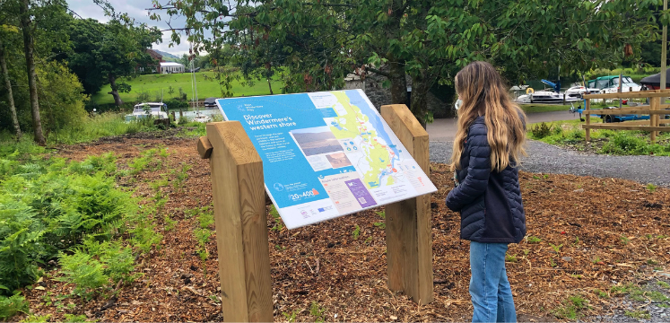 A  young woman looks at one of the interpretation panels on the route 