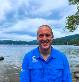 New Chief Executive Gavin Capstick with lake behind him 