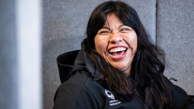 Female staff member laughing. The photograph shows her arms and, shoulders and head shot. She is waering a black jacket with LDNPA and IK national Parks logos. 