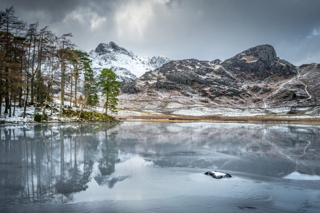 View across Blea Tarn in the Langdales during winter with snow on the mountains in the background