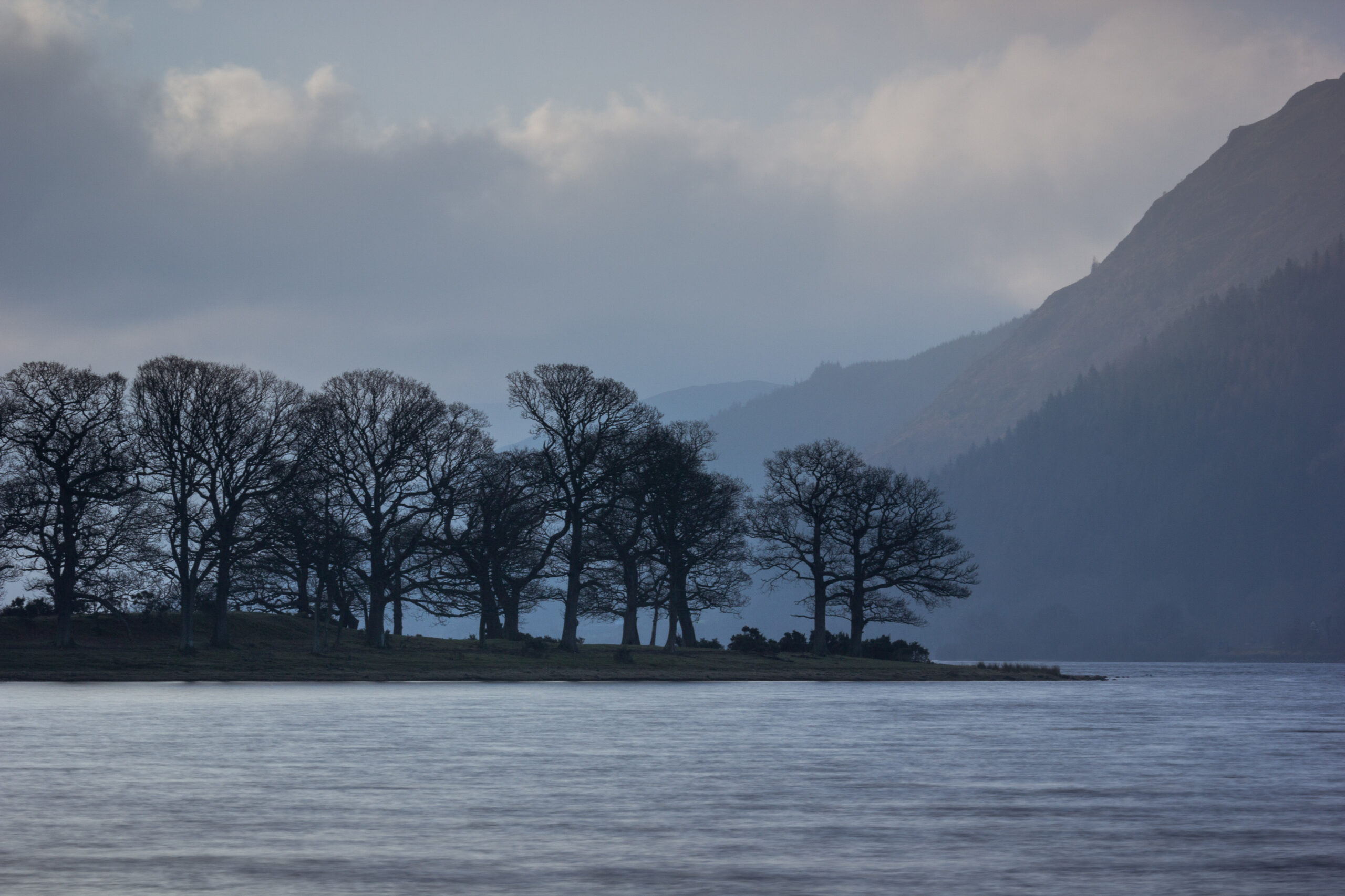 landscape view of Bassenthwaite lake with trees and silhouette of mountains
