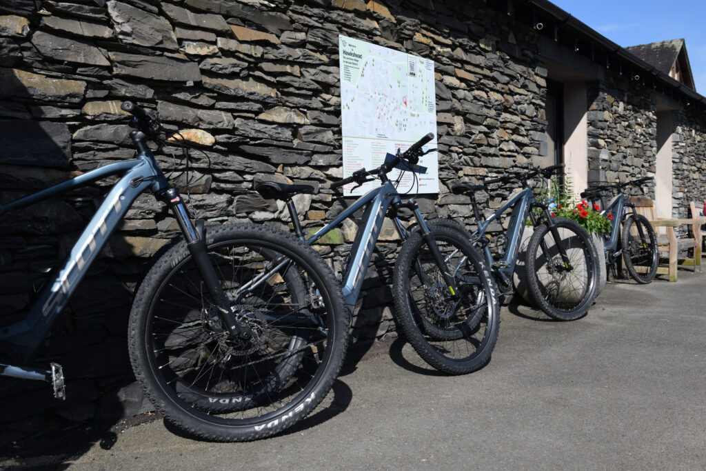 Mountain bikes on grey tarmac propped against grey slate wall