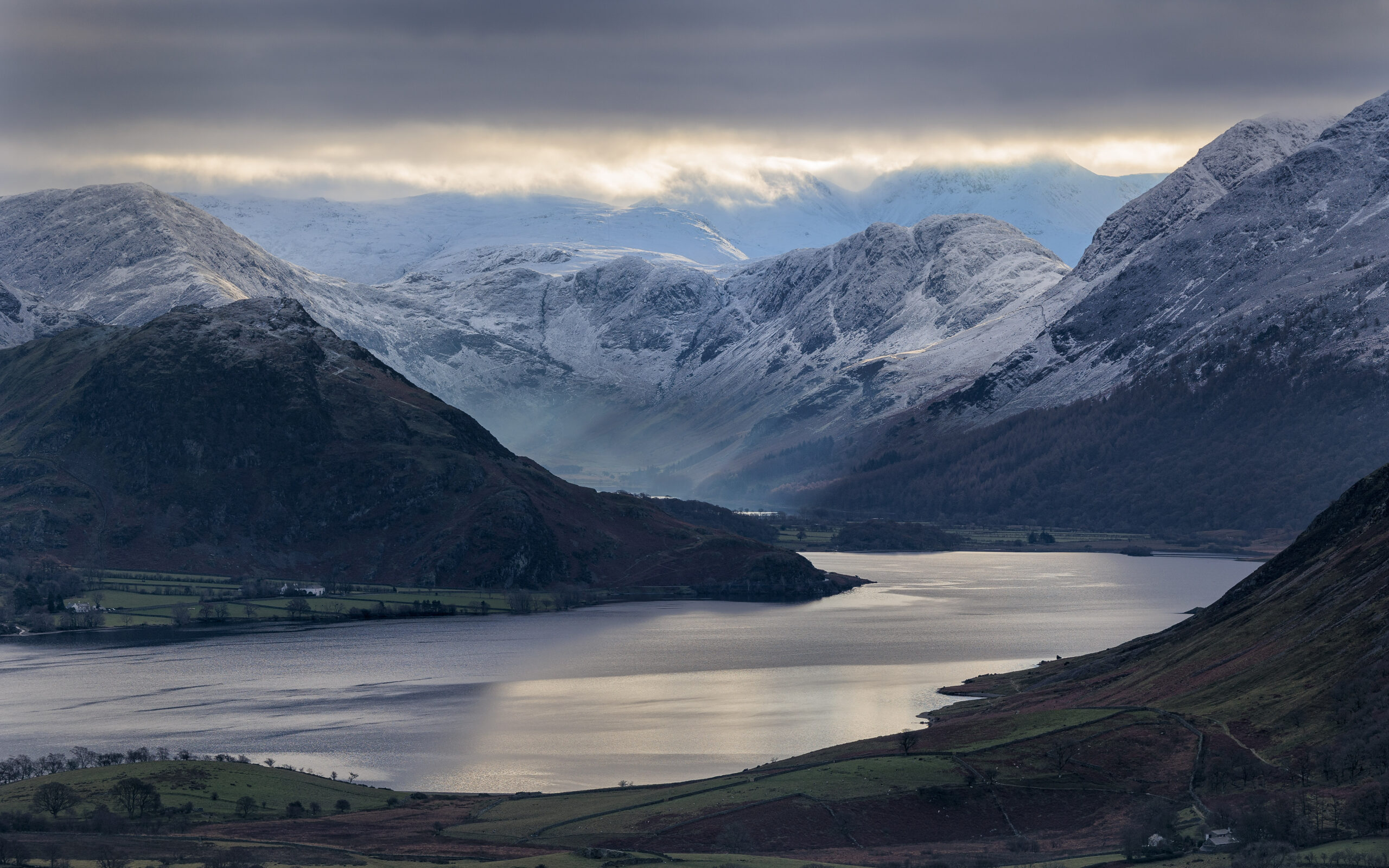 Landscape view of crummock water. dark day, shadowed snow-topped fells