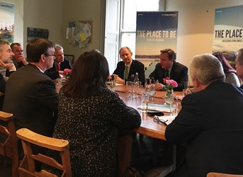table of adults in smart clothing facing into the centre of the table in an office