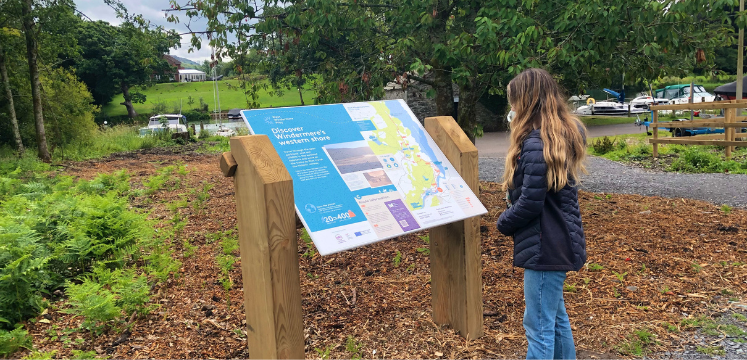 A young woman looks at one of the interpretation panels on the route