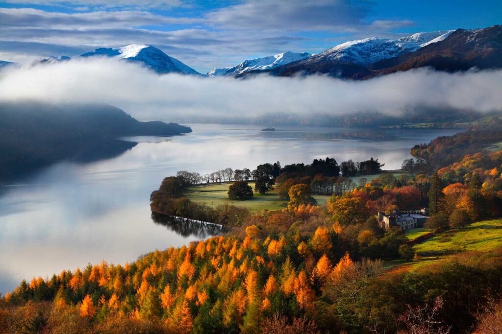 Overlooking Ullswater with cloud inversion below the mountain peaks with grass land sticking out into the water