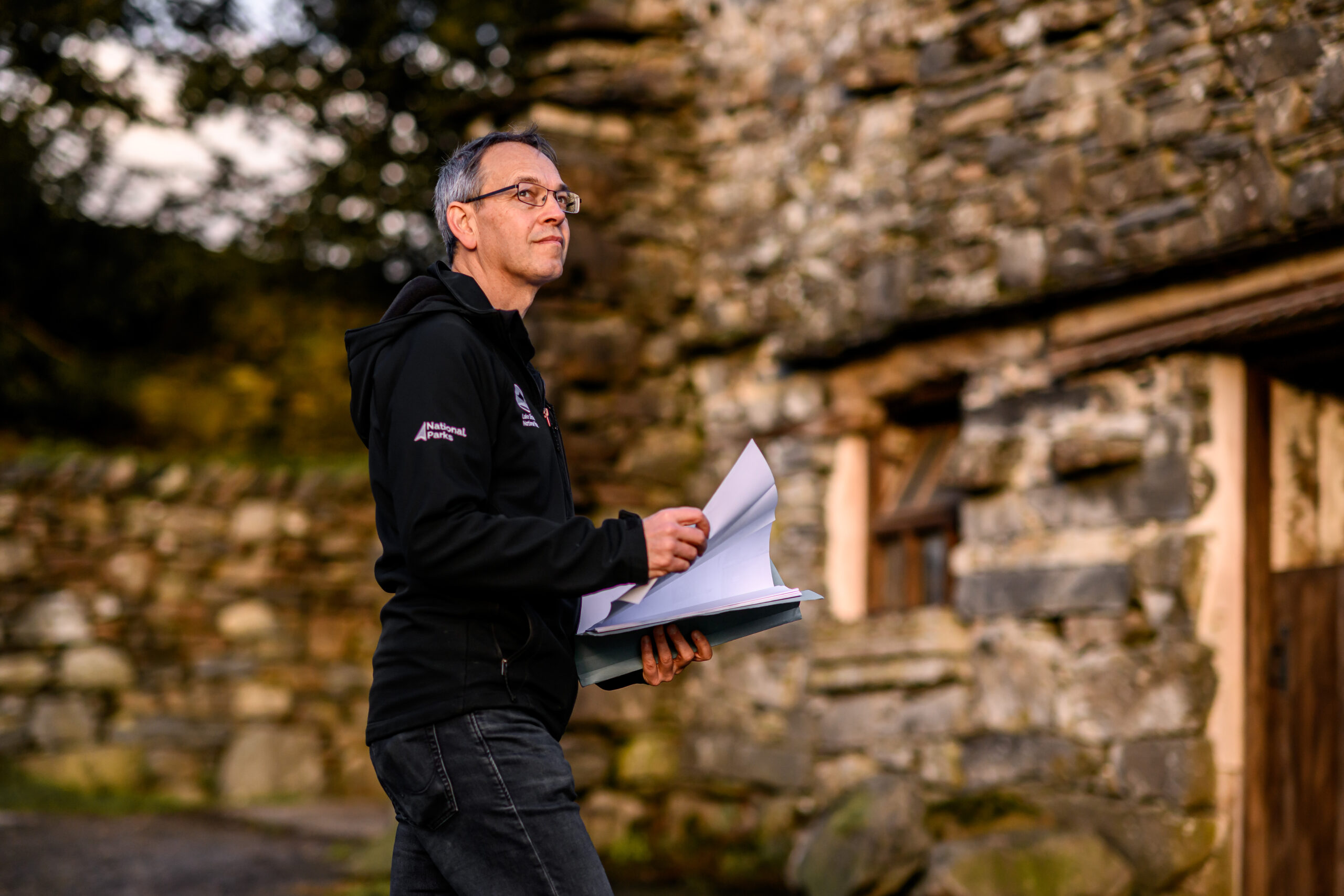 lake district national park planning officer holding white paper in front of a stone building