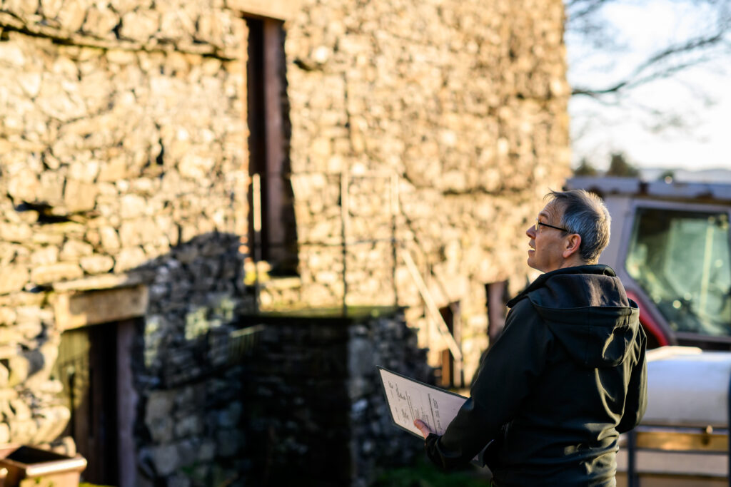 lake district national park planning officer holding white paper in front of a stone building
