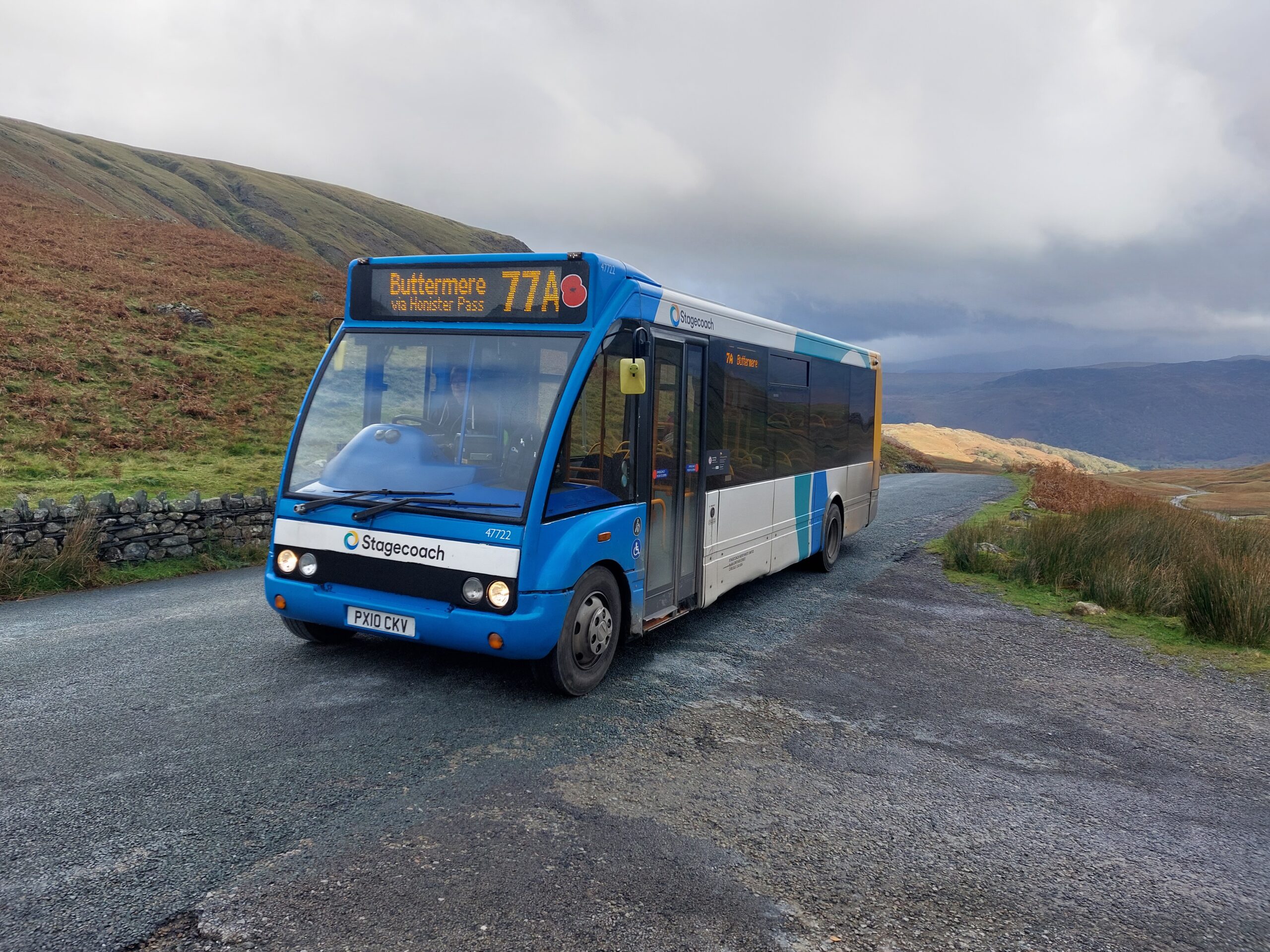 blue single decker 77a bus parked on honister pass on a gloomy day