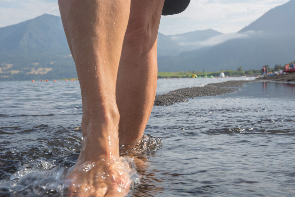 bottom half of bare legs walking through shallow water