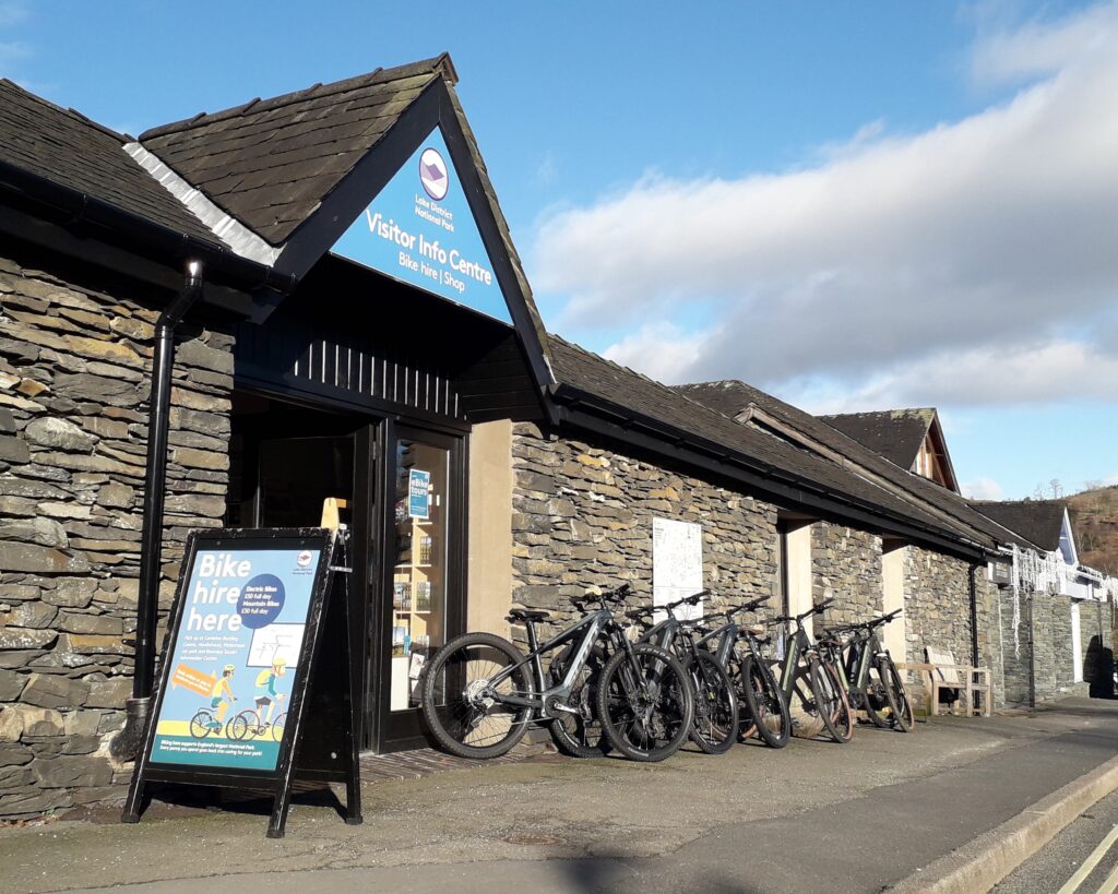 hawkshead bike hire at the information centre. bikes lines up by slate stone wall of building