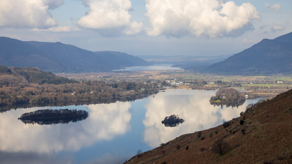 landscape view of borrowdale, glassy lake with surrounding shadowed fells