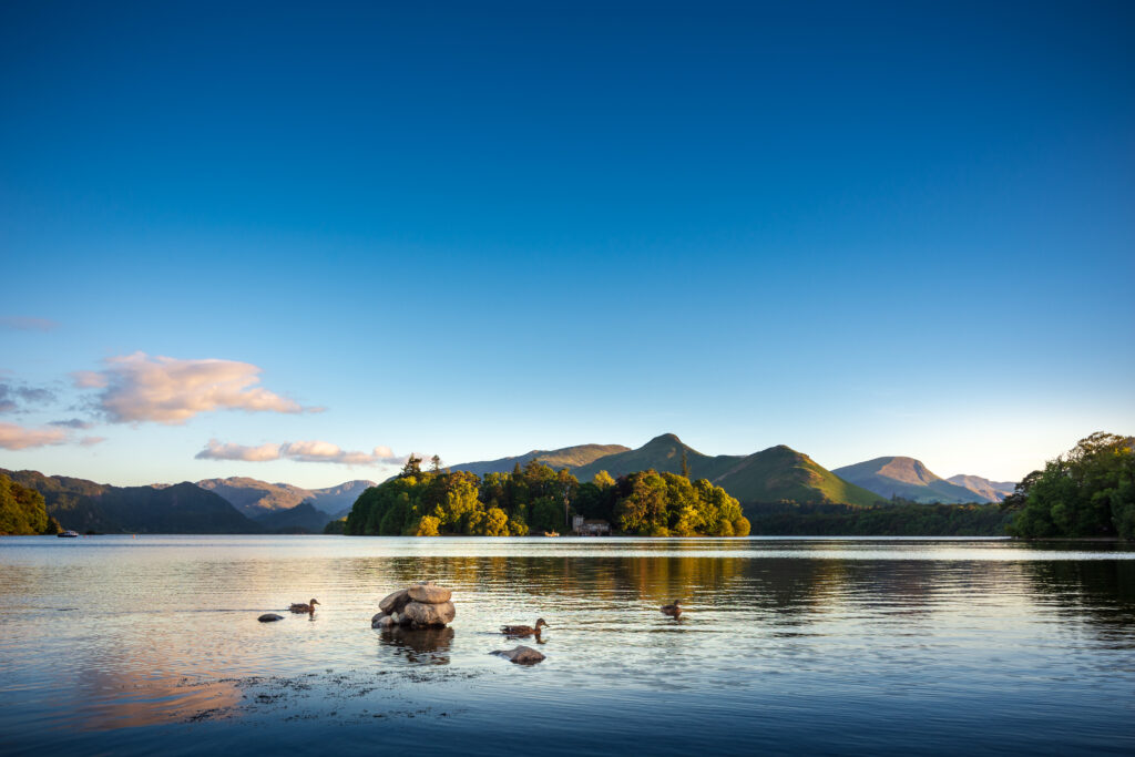 derwent isle on a bright day. still lake surface reflecting distant fells