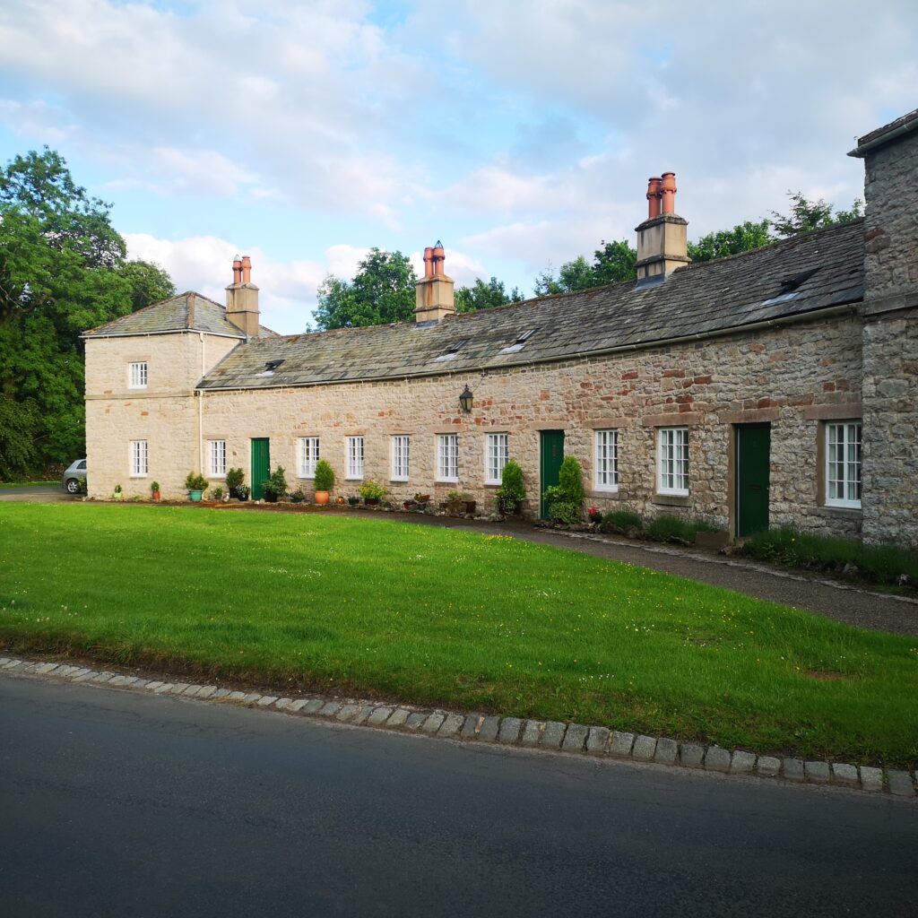 terrace of rural brick houses behind patch of well kept grass and road