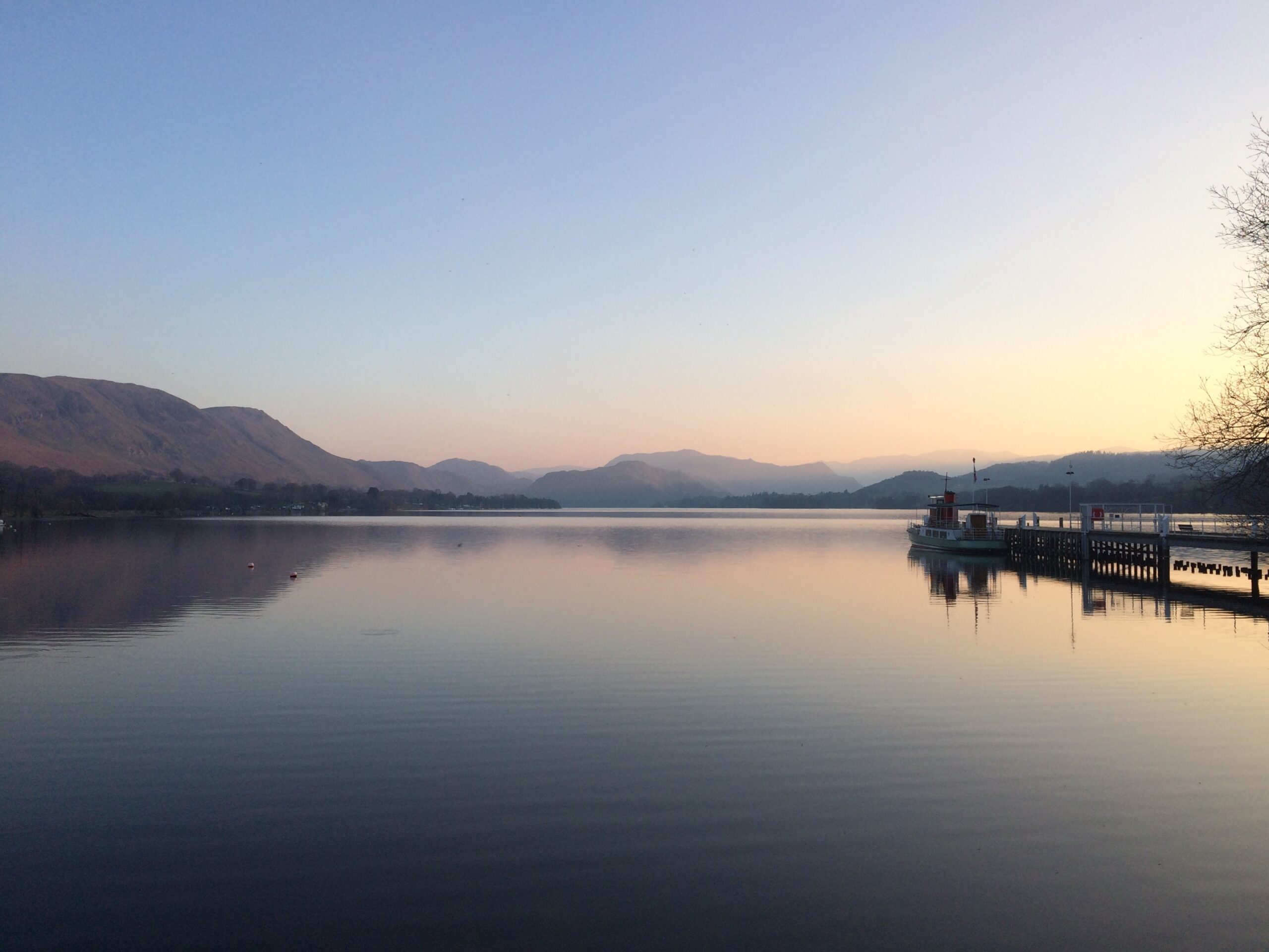 sunset and clear sky looking out over ullswater with jetty to right