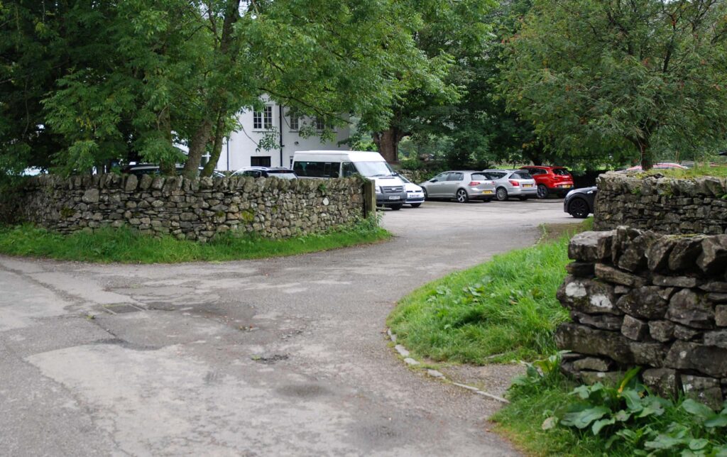 track entrance lined by dry stone walls and woodland to rosthwaite car park