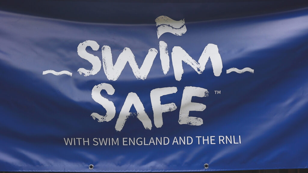 full screen navy banner flag reading Swim Safe, with Swim England and the RNLI in white lettering
