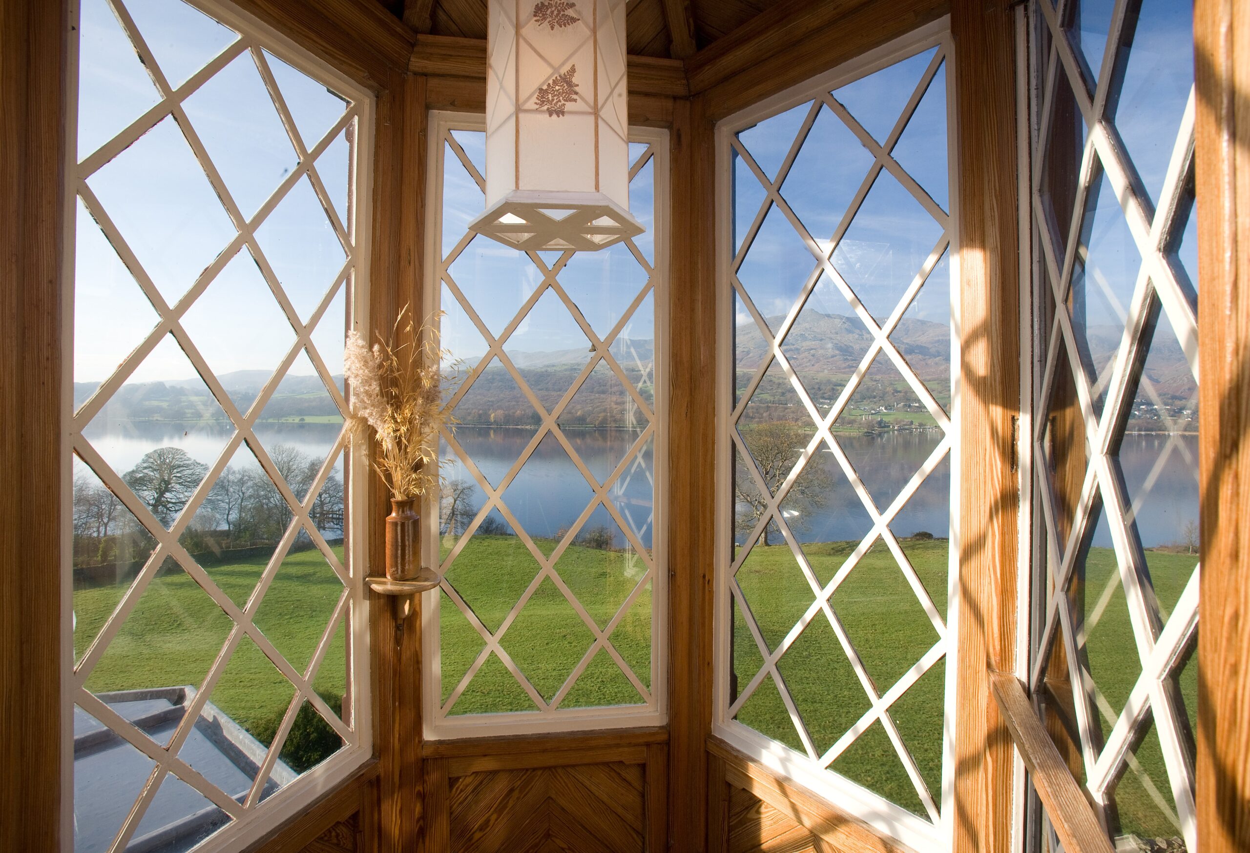 inside of brantwood house looking out through large curved wooden framed window with white sashes