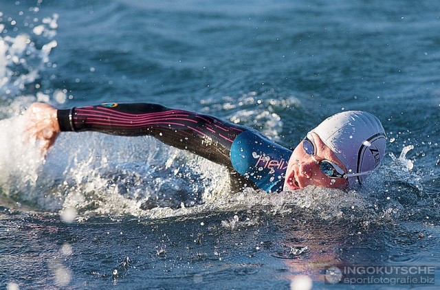 close up of adult female in wetsuit, goggles and swim hat swimming in the lake