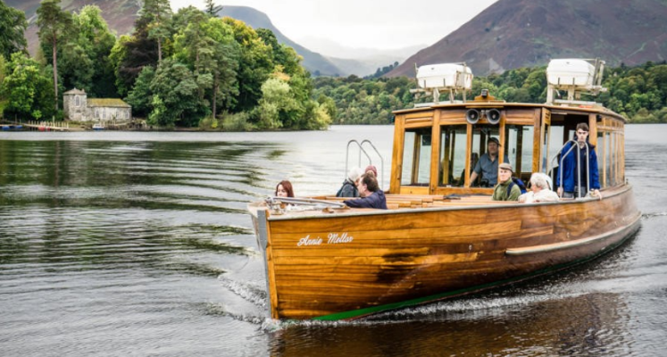 Boat on the lake with public onboard surrounded by Lake District hill views