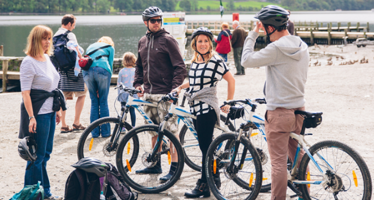 Cyclists stood by their bikes on the lake with the lake and jettys in the background 