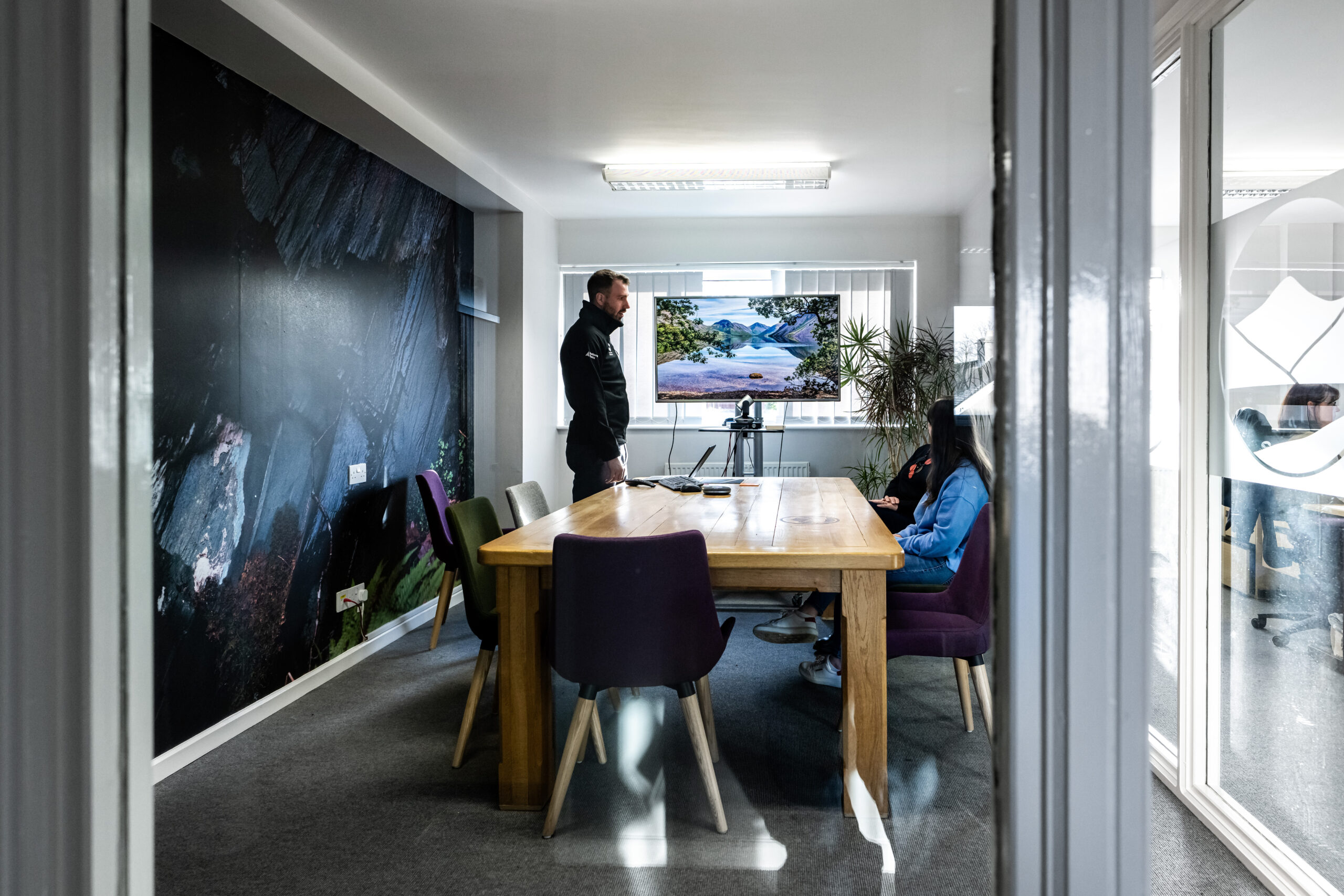three adults around a table in a meeting room