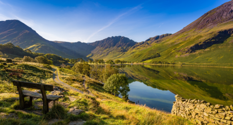 View of a bench looking over Buttermere with fells reflecting in the water