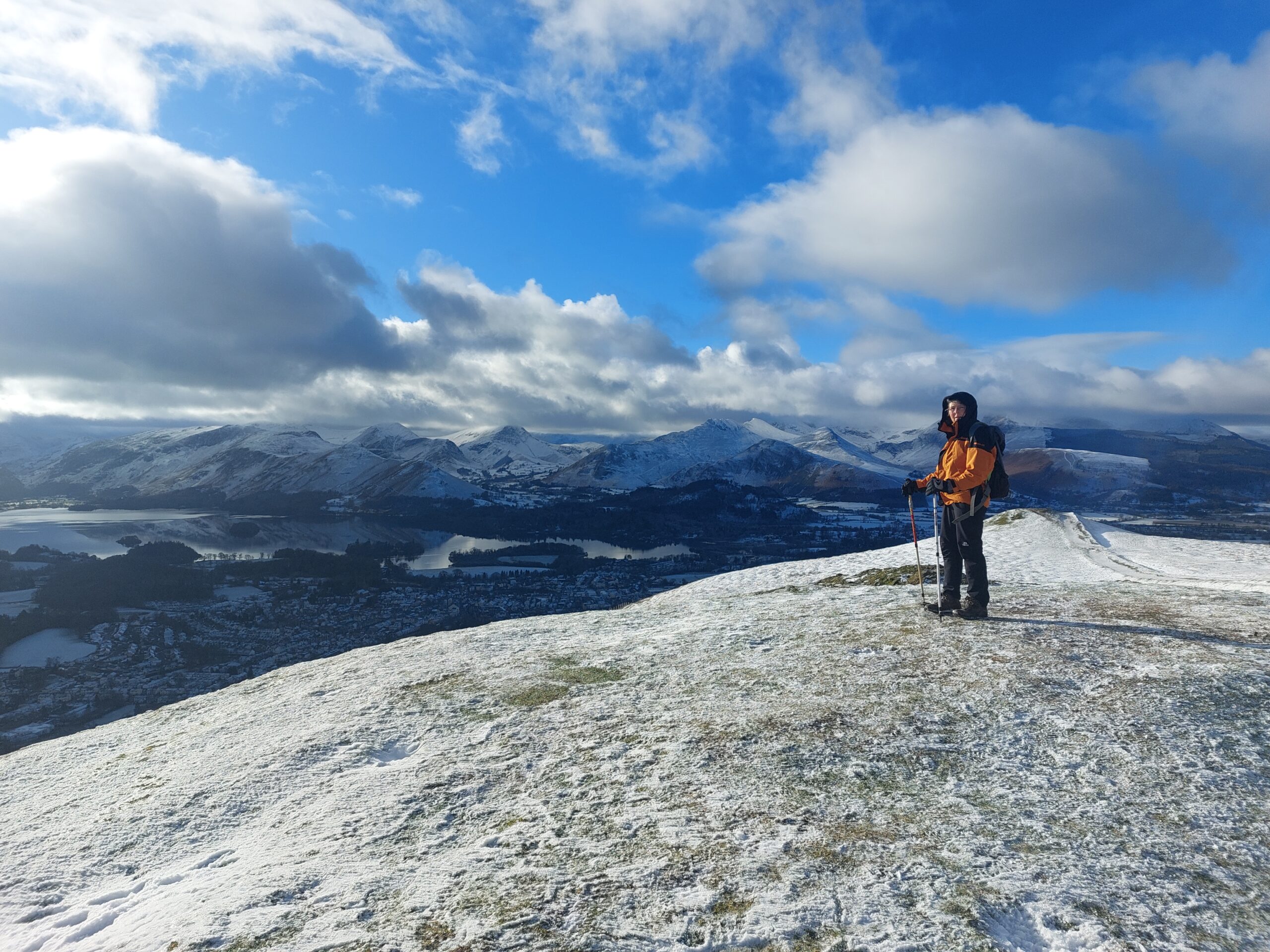 Ron stood in all waterproofs on top of Latrigg dusted in snow overlooking Borrowdale