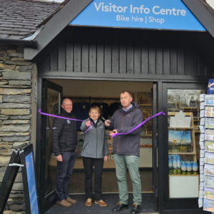 Three people opening a visitor information centre cutting a purple ribbon