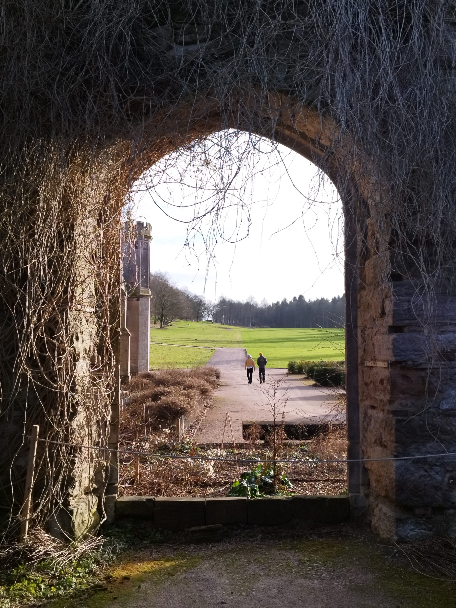 Lowther Castle looking through archway at people walking in garden