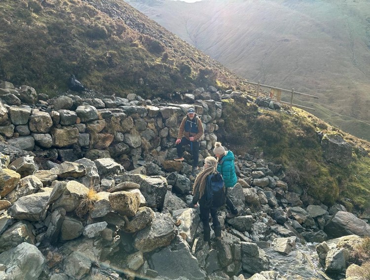 repaired fell wall with three people viewing it