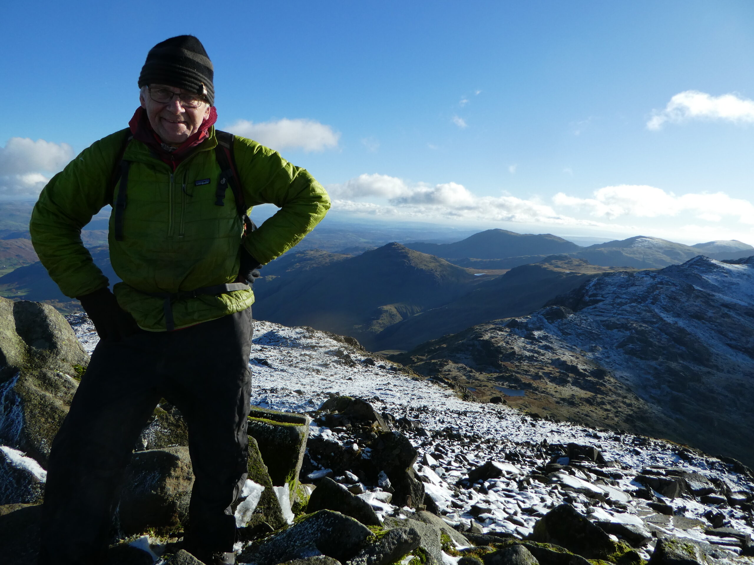 Ron Kenyon stood on the top of Bowfell with a dusting of snow with views towards Pike o'Blisco