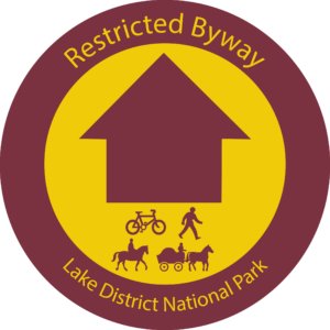 burghandy waymarker roundel with yellow circle and burghandy arrow. Bike, person, horse and horse and cart symbols with text saying restricted byway