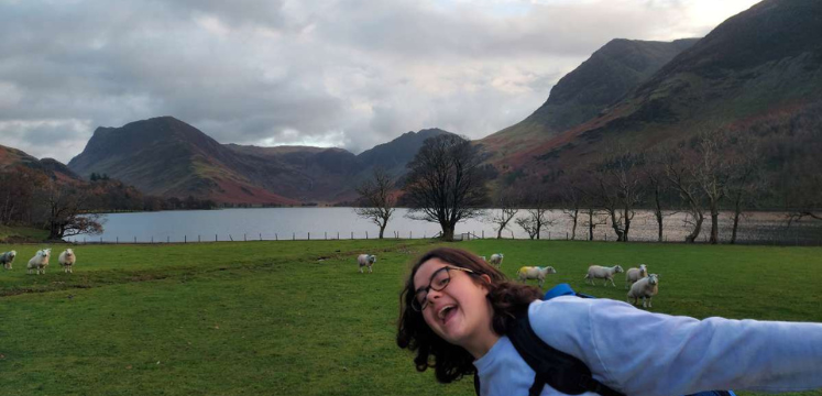Amy in the Lake Distrcit with thumbs up and sheep in background