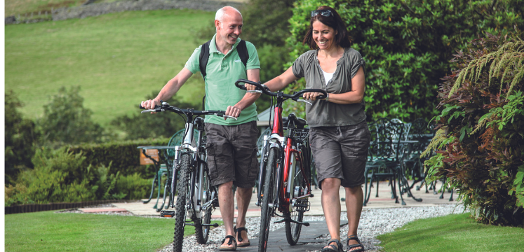 man and woman walking with electric bikes