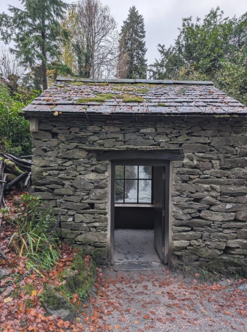 Small stone building next to river at Rydal with window looking at waterfall