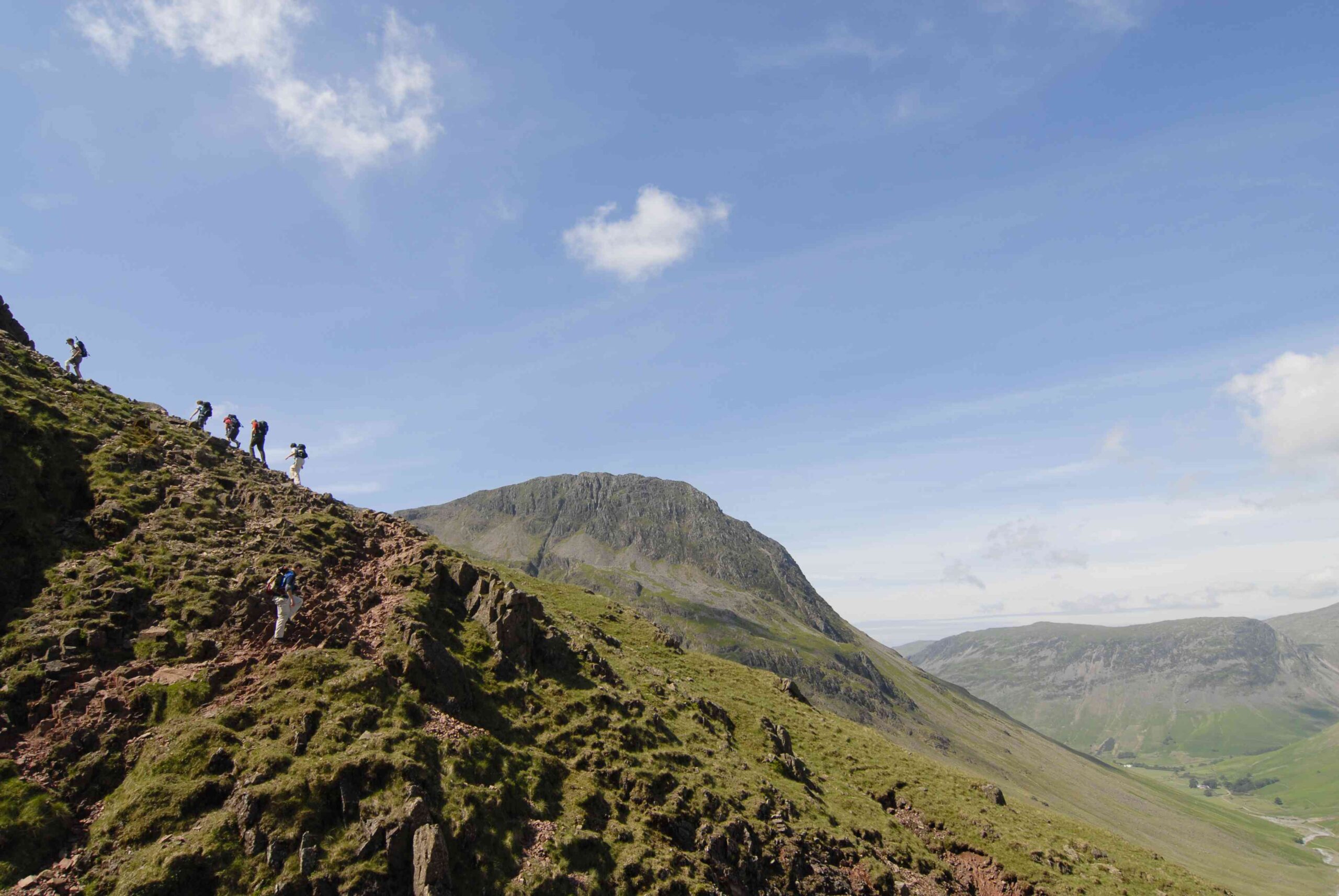 group of adults hiking up scafell pike fells on a sunny day